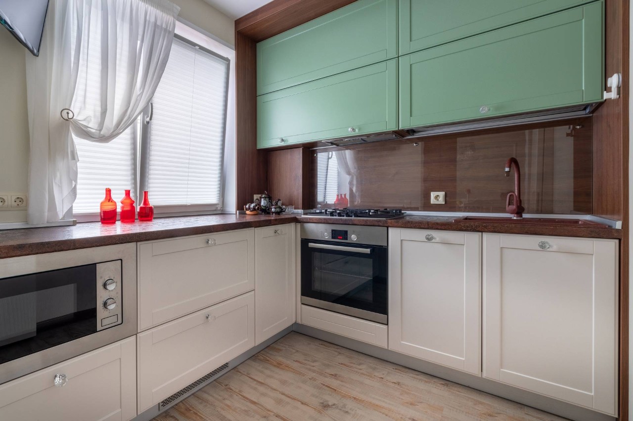 A kitchen with a window over the counter and green cabinetry at Amazing Blinds & Shutters near Amarillo, Texas